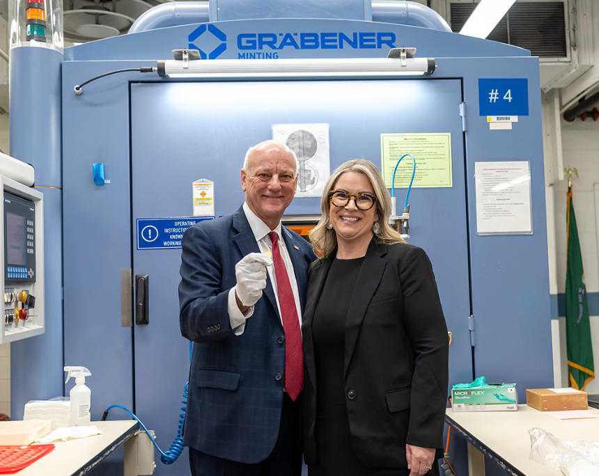 Brandon Beach, US Treasurer, und Kristie McNally, US Mint Acting Director, halten zwischen sich einen der Omega-Pennys nach der Prägung. Foto: US Mint