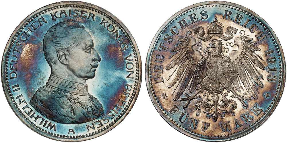 Eine Regenbogenpatina hat ihren Namen davon, dass sie beim Drehen einer Münze in allen Farben des Regenbogens schillert, ungefähr so wie auf dieser Münze: Preußen. Wilhelm II. 5 Mark 1913. Polierte Platte. Startpreis: 400 Euro. Aus Auktion Heidelberger Münzhandlung 94 (10.-12. November 2026), Nr. 3527.